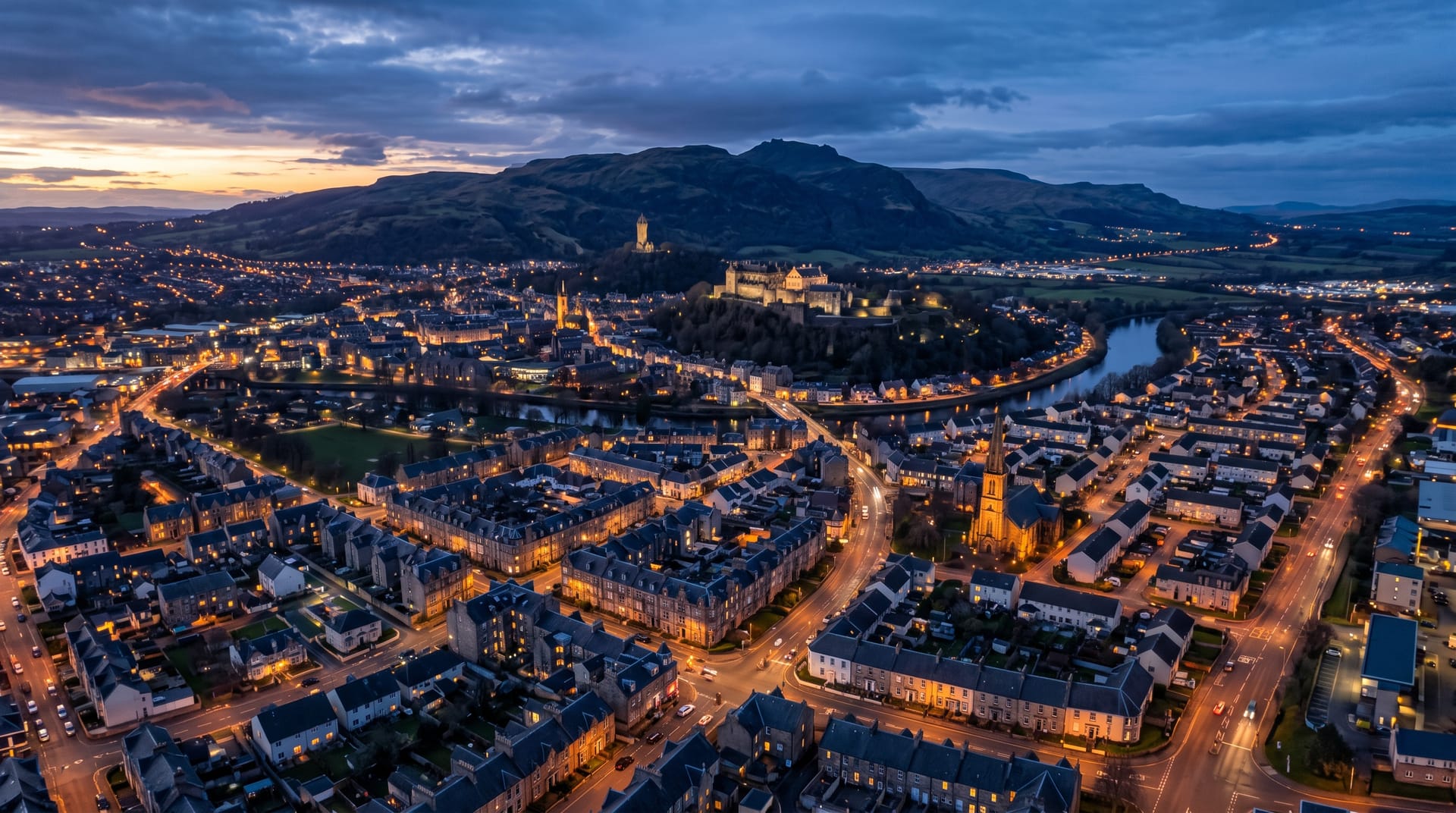 Homes across a central Scotland town at dusk with Stirling Castle on the skyline